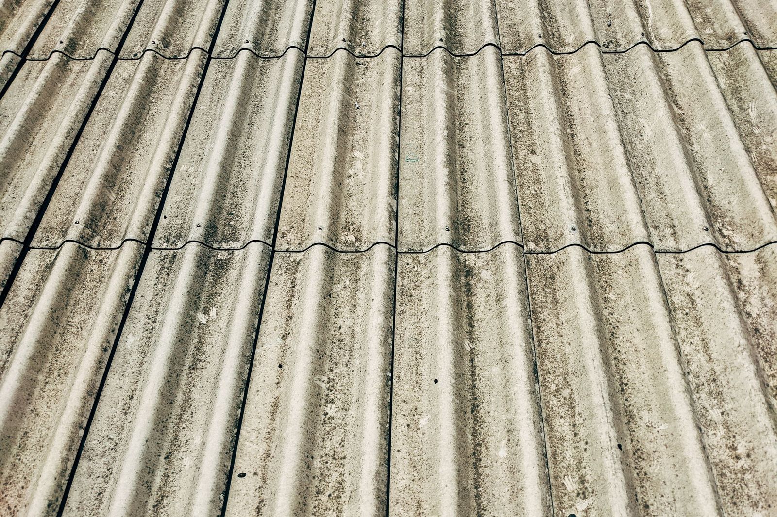 Szare faliste płyty eternitu na dachu, z zabrudzeniami