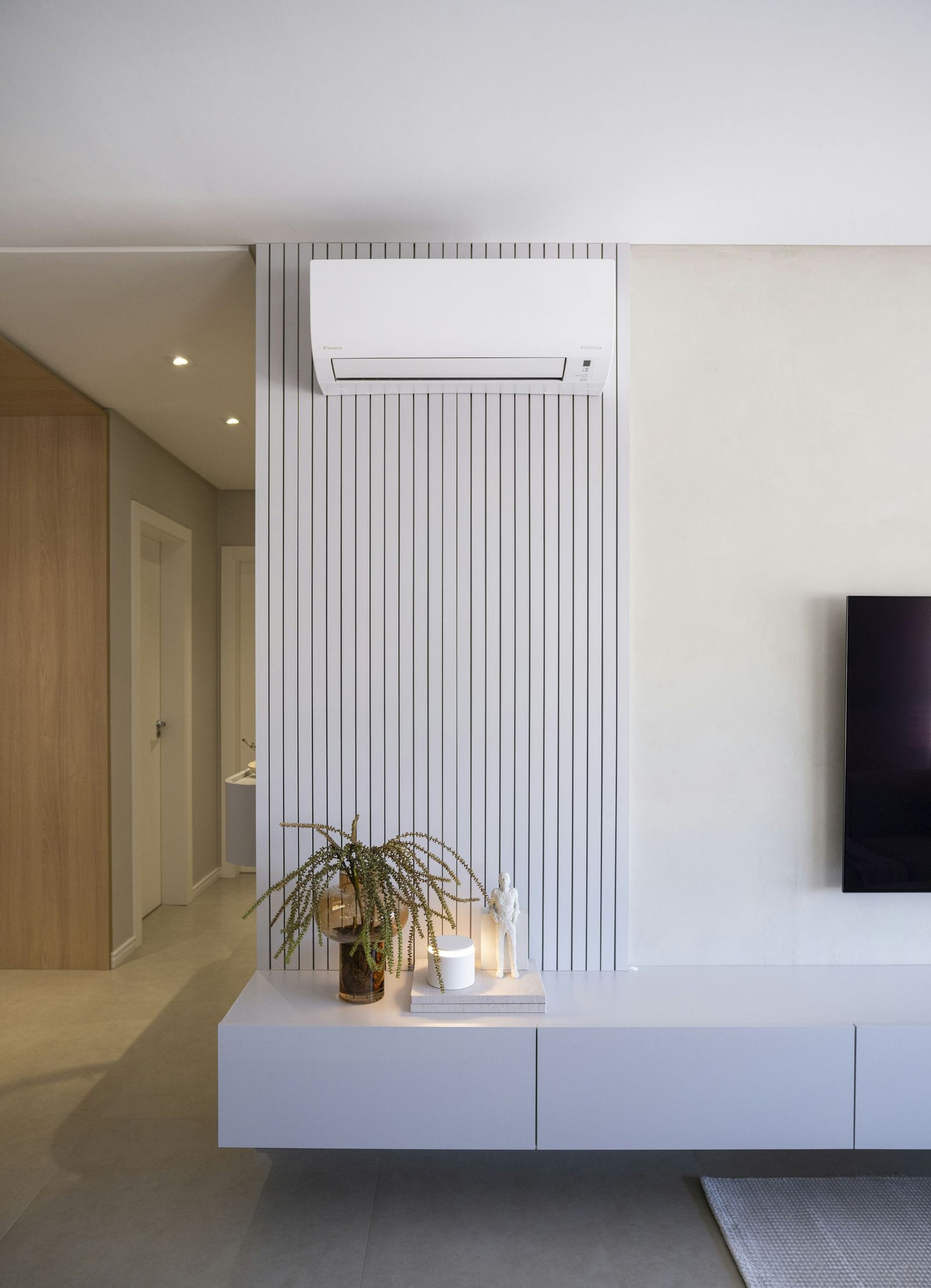 Jasny salon z klimatyzatorem ściennym nad drewnianą lamelową ścianą